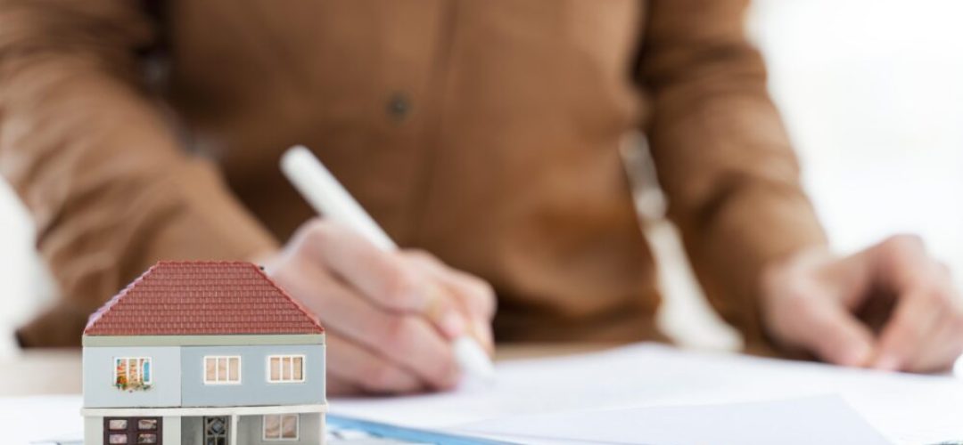 realtor-signing-contract-clipboard-miniature-house-1-scaled